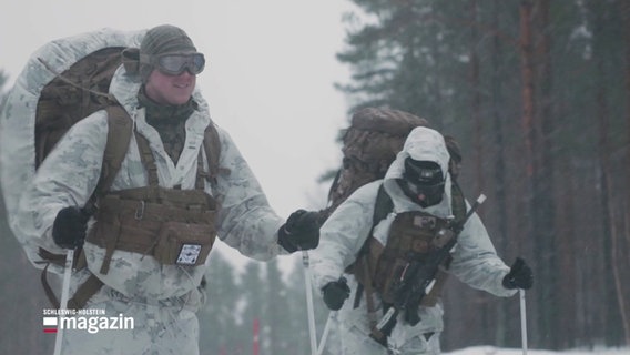 Zwei uniformierte Soldaten gehen mit Wanderstöcken durch einen Schneesturm. © Screenshot 