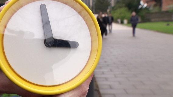 Eine Uhr aus Plastik wird eine Stunde vor gestellt. © Screenshot 