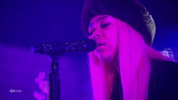 Die Sängerin Zoe Wees steht in blau-violettem Licht auf der Bühne. © Screenshot 