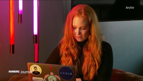 Eine Frau mit langen roten Haaren sitzt an einem Laptop (Archivbild). © Screenshot 