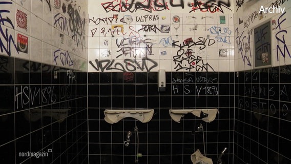 Zwei abgerissene Waschbecken und vollgeschriebene Fliesen auf dem Herrenklo. © Screenshot 