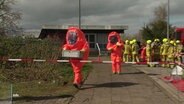 Arbeiter in leuchtend oranger Schutzkleidung beim Gefahrgut-Einsatz am Güterbahnhof in Hannover, © Screenshot 