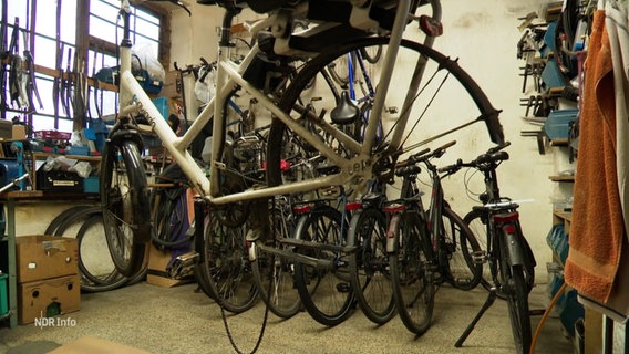 Ein Fahrrad mit ausgebautem Hinterrad hängt auf einem Ständer in einer Fahrrad-Werkstatt. © Screenshot 
