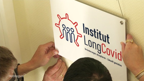 Ein Schild mit dem Logo und Schriftzug des LongCovid Instituts wird von der Wand genommen. © Screenshot 
