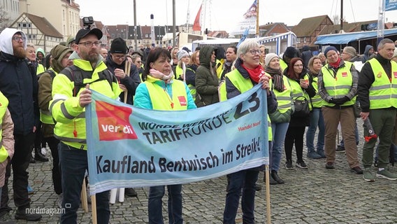 Streikende Menschen in gelben Warnwesten, im Vordergrund halten mehrere Personen ein Banne mit der Aufschrift: "Tarifrunde - Kaufland Bentwisch im Streik!" © Screenshot 