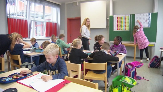 In einem Schulraum sitzen einige Kinder und arbeiten zusammen. © Screenshot 