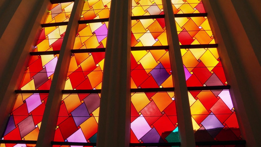 Ein Kirchenfenster im Greifswalder Dom zeigt ein abstraktes Muster warmer Farben.
