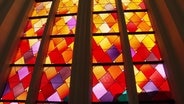 Ein Kirchenfenster im Greifswalder Dom zeigt ein abstraktes Muster warmer Farben. © Screenshot 
