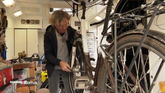 Stephan Röper ist Zweiradmechanikermeister und arbeitet in seiner mobilen Reparaturwerkstatt an einem Fahrrad. © Screenshot 