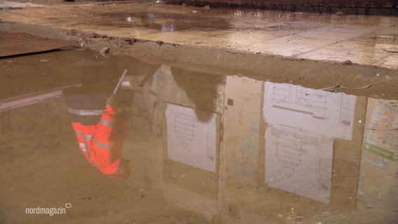 Ein Bauarbeiter speichert sich in einer Pfütze. © Screenshot 