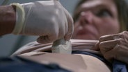 Der Bauchraum einer Frau wird mit einem Ultraschallgerät gescannt. © Screenshot 