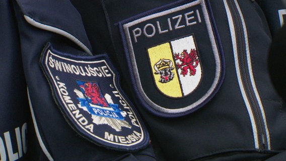 Das Bild zeigt zwei Uniformjackenärmel, wobei der eine ein polnisches und der andere ein deutsches Polizeiwappen zeigt. © Screenshot 