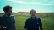 Altkanzler Gerhard Schröder und der Journalist Lucas Stratmann laufen über einen Golfplatz. © Screenshot 