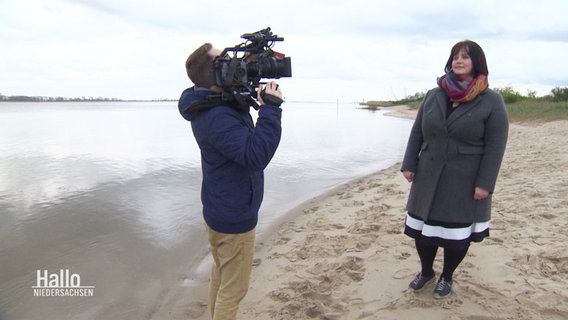 Eine Frau wird an einem Strandabschnitt von einem Kameramann begleitet. © Screenshot 