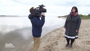 Eine Frau wird an einem Strandabschnitt von einem Kameramann begleitet. © Screenshot 