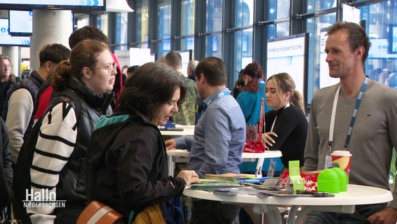 Menschen auf einer Messe mit Ständen. © Screenshot 