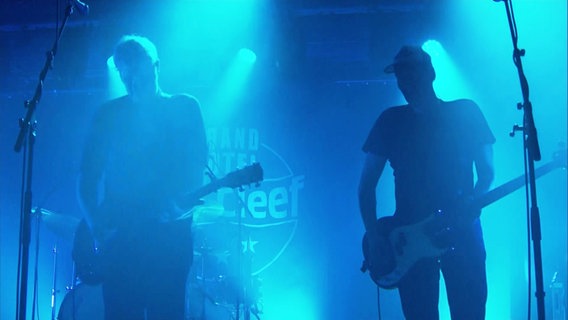 Mitglieder der Band "Kettcar" auf einer in blaues Licht gehüllten Bühne. © Screenshot 