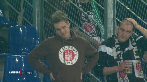 Zwei St. Pauli Fans stehen auf der Tribüne und sehen etwas niedergeschlagen aus. © Screenshot 