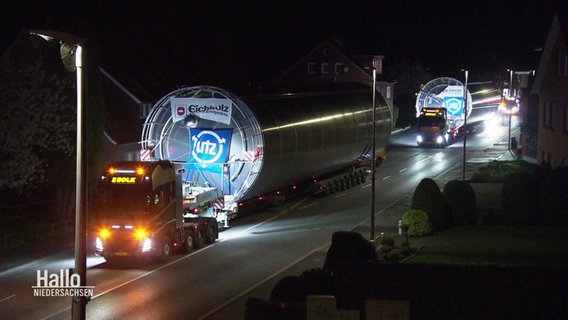 Zwei mit großen Metall-Silos beladene Schwertransporter fahren bei Nacht auf einer Straße. © Screenshot 