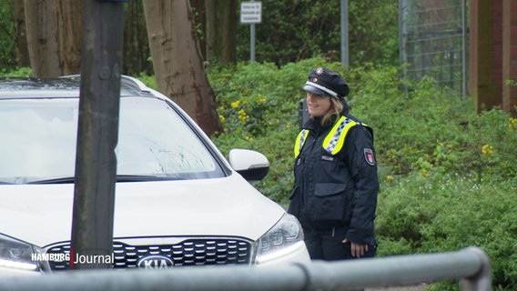 Eine Polizistin steht neben einem SUV mit offenen Fenster zum Gespräch. © Screenshot 