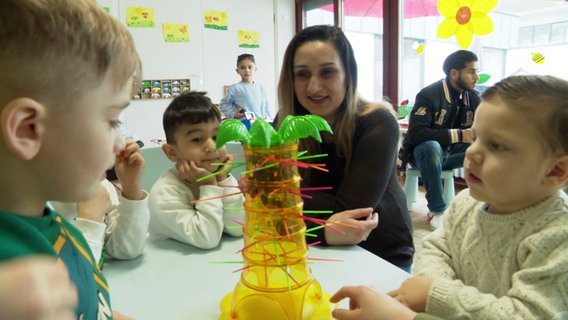 Eine Frau sitzt mit Kindern an einem Tisch. © Screenshot 