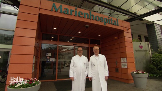 Zwei Ärzte in wewißen Kitteln stehen vor dem Marienhospital. © Screenshot 
