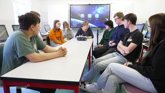 Menschen sitzen zusammen an einem Tisch. © Screenshot 