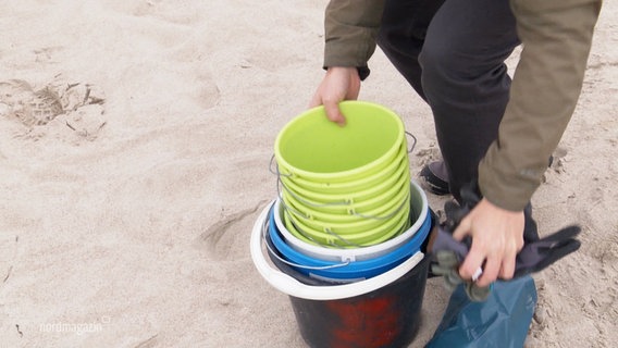 Am Strand der Ostsee werden Eimer zum Sammeln von Müll verteilt. © Screenshot 