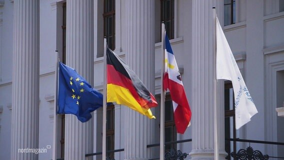 Flaggen wehen im Wind. Darunter die blaue EU-Flagge mit den Sternen, die deutsche und die Bundeslandflagge von Mecklenburg-Vorpommern. © Screenshot 