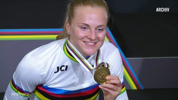 Die Bahnradsportlerin Friedrich hält ihre Goldmedaille in die Kamera. © Screenshot 