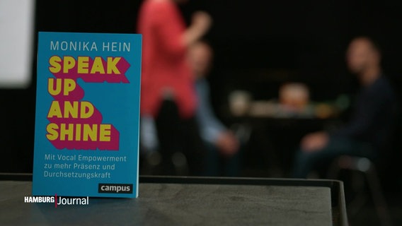 Ein Buch mit dem Titel "speak up and shine" steht auf einem Tisch. © Screenshot 