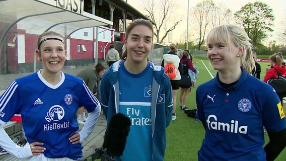 Drei junge Frauen im Interview. Zwei tragen ein Trikot von Holstein Kiel, die in der Mitte ein Trikot vom HSV. © Screenshot 