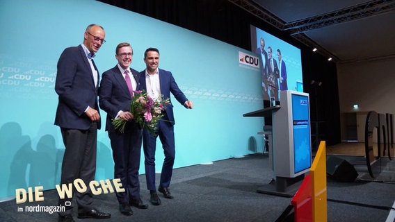 Friedrich Merz, Philipp Amthor und Daniel Peters stehen auf einer Bühne. © Screenshot 