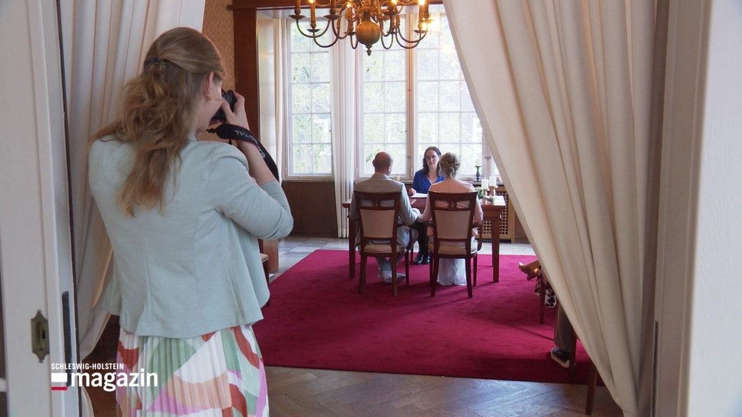 Ein Blick in den Saal des Elmshorner Standesamts: Darin ein Brautpaar und eine Standesbeamtin.
