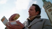 Jo Hiller nimmt einen Burger aus einer Pappschachtel. © Screenshot 