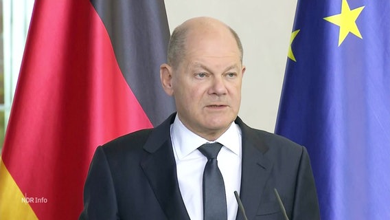 Bundeskanzler Olaf Scholz bei einem Statement. Im Hintergrund Deutschland- und Europaflagge. © Screenshot 