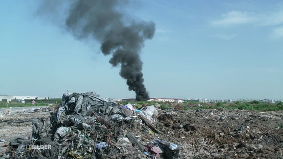 Schwarzer Rauch steigt aus einer Müllhalde empor. © Screenshot 