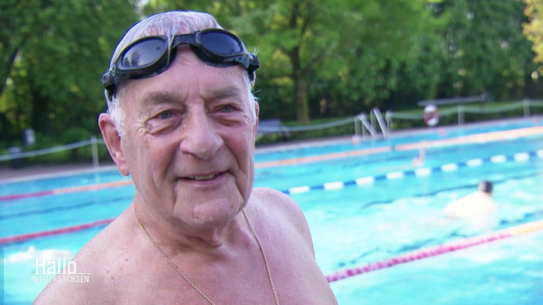 Ein älterer Herr mit Schwimmbrille in einem Freibad.