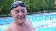 Ein älterer Herr mit Schwimmbrille in einem Freibad. © Screenshot 