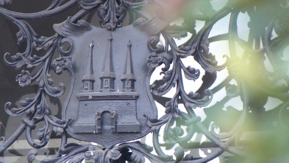 Das metallene Wappen Altonas zeigt eine Burg mit offenen Toren. © Screenshot 