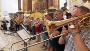 Eine Gruppe Blechbläser in einer Kirche, von der Seite fotografiert. © Screenshot 