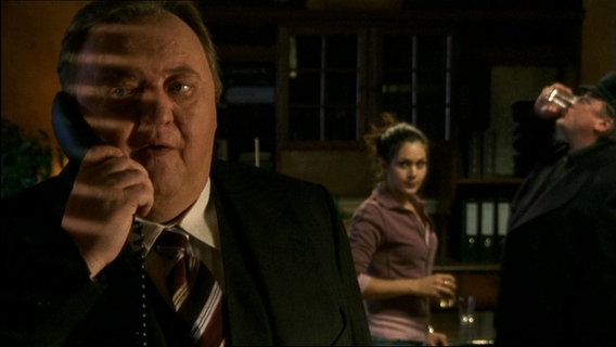 Der Dicke geht ans Telefon während im Hintergrund Schnaps getrunken wird. © Screenshot 