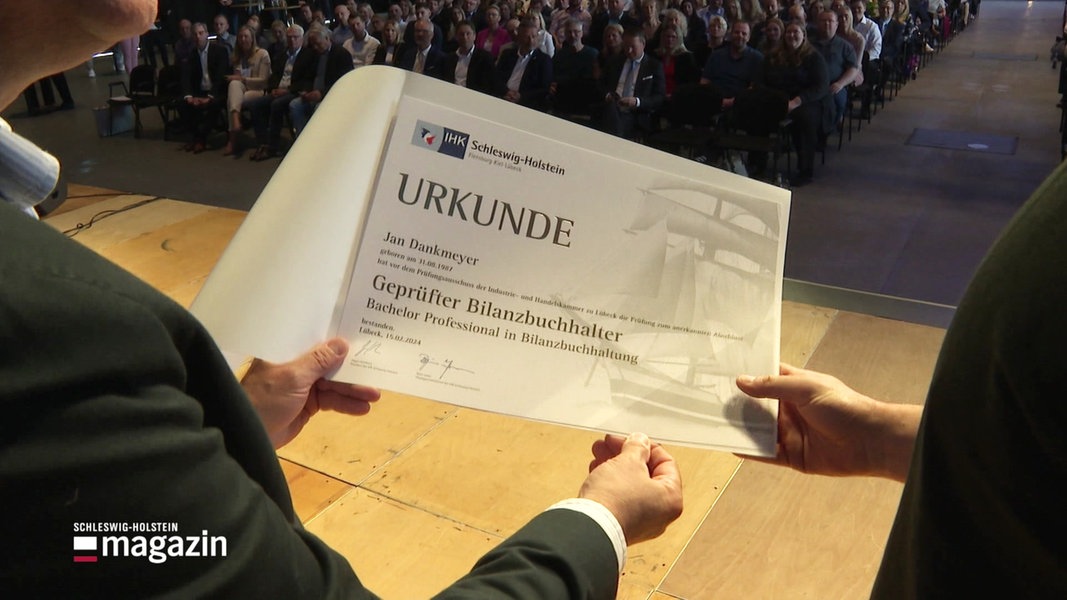 Ein Absolvent bekommt bei der Meisterfeier der Industrie- und Handelskammern in Lübeck seine Urkunde überreicht.