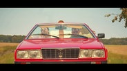 Die drei Sänger der Band Schorl3 sitzen in einem roten Cabriolet. © Screenshot 