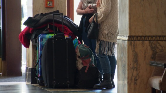 Zwei Frauen stehen mit ihren Koffern in einer Hotellobby.  © Screenshot 