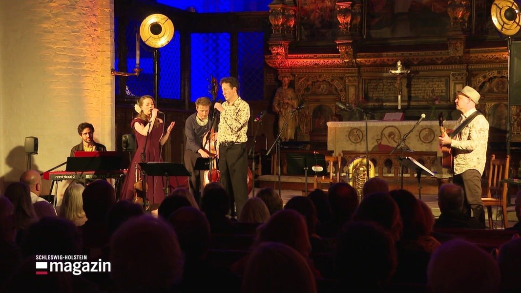 Musiker in einer Kirche vor einem Altar in Licht gehüllt.