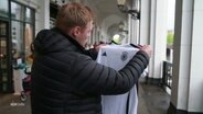 Ein Mann hält ein Trikots der Deutschen Fußballnationalmannschaft in den Händen. © Screenshot 
