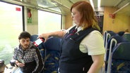Eine Zugbegleiterin kontrolliert das Ticket eines Reisenden. © Screenshot 