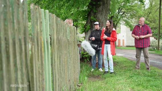 Menschen stehen an einem Gartenzaun. © Screenshot 