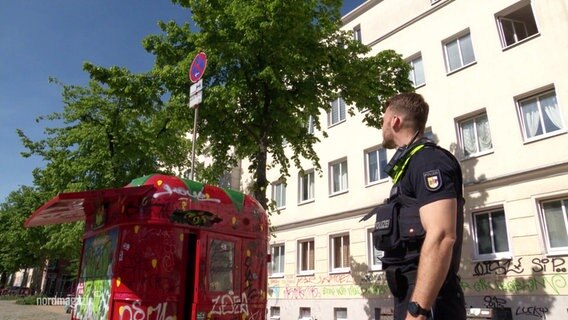 Ein Polizist schaut sich auf einem Platz um. © Screenshot 